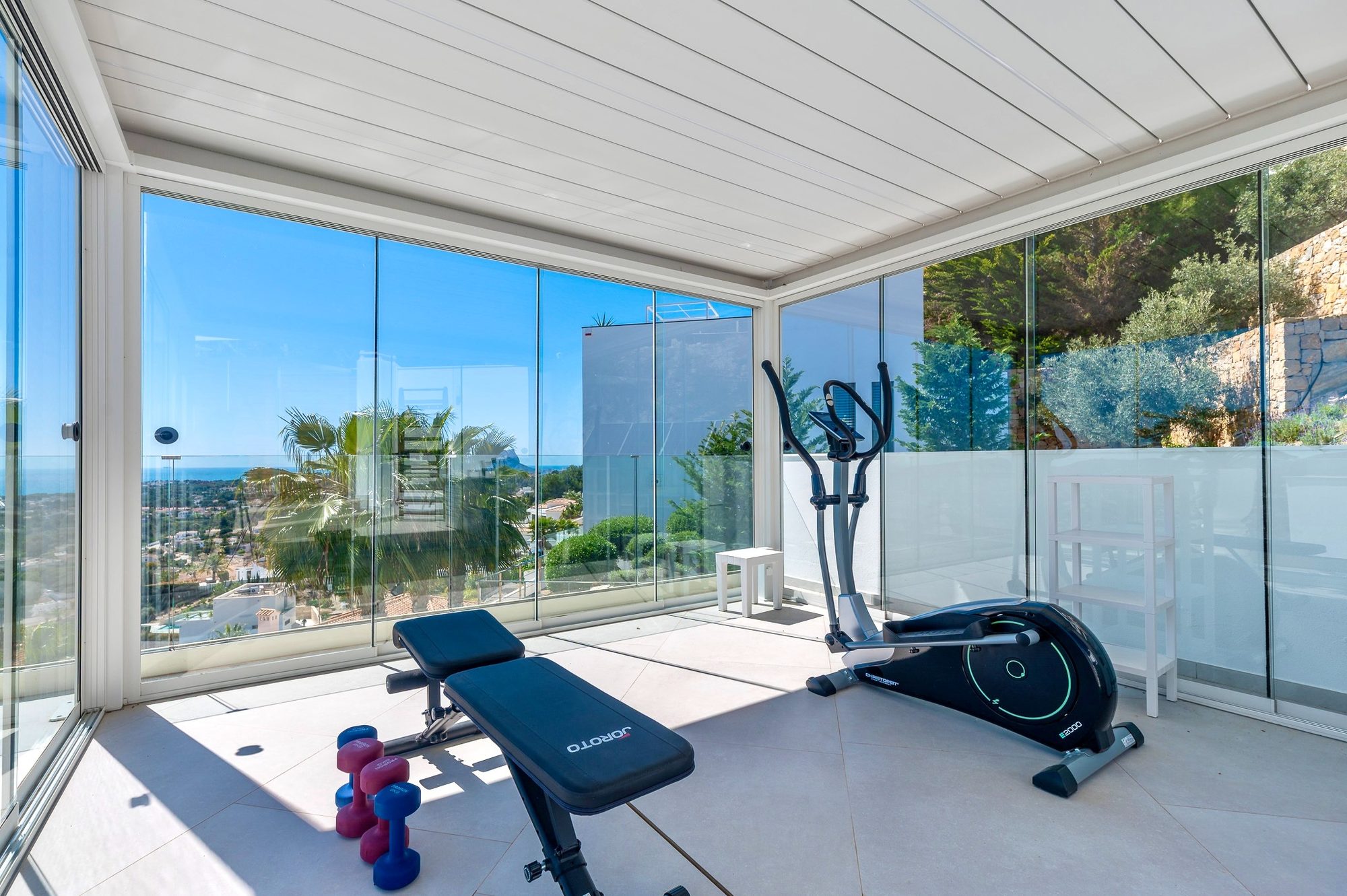 Klimatisiertes Fitnessstudio in der verglasten Pergola mit Meerblick
