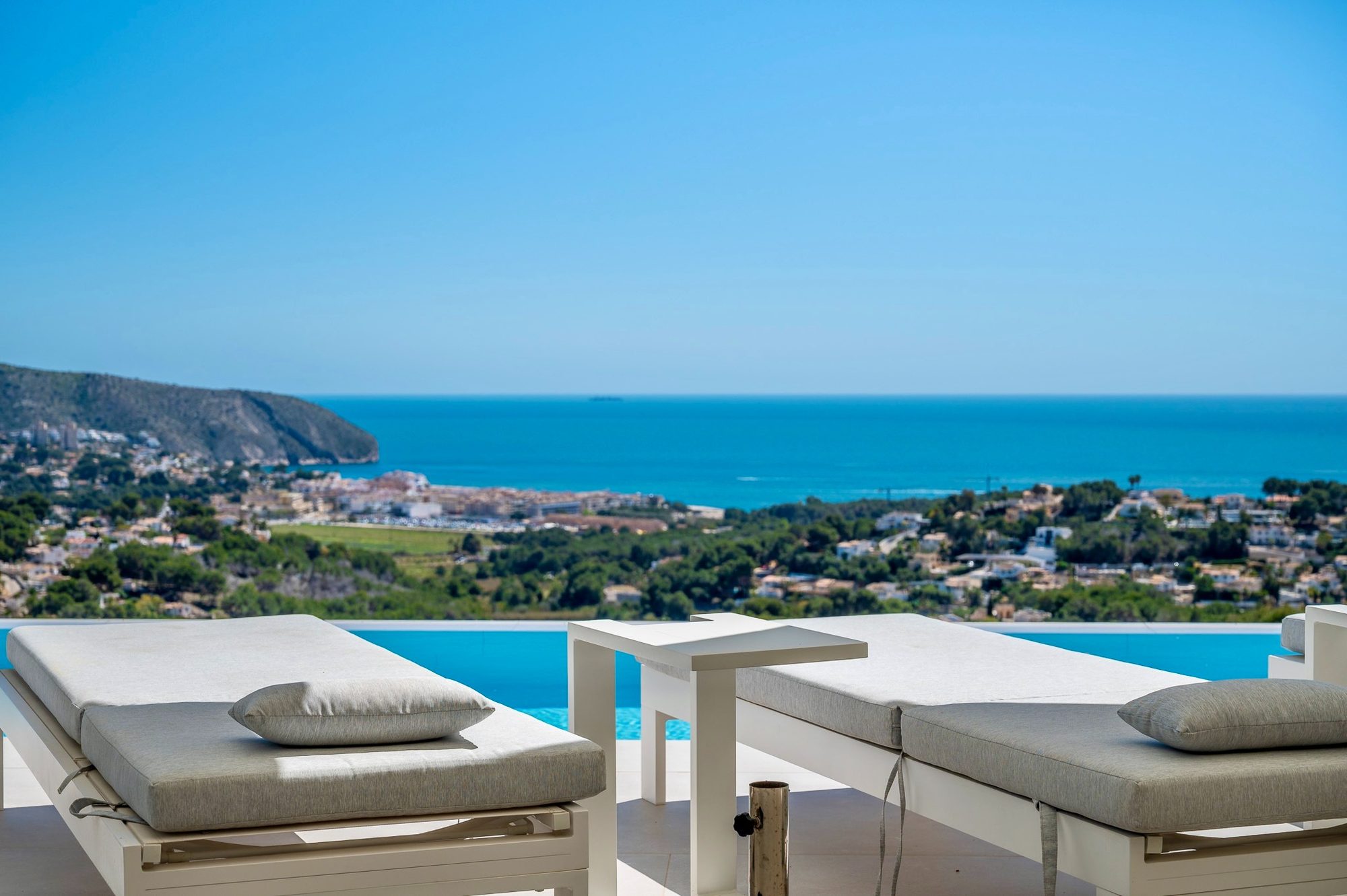 Zwei Sonnenliegen an der Infinity-Kante des Pools mit Blick über Moraira