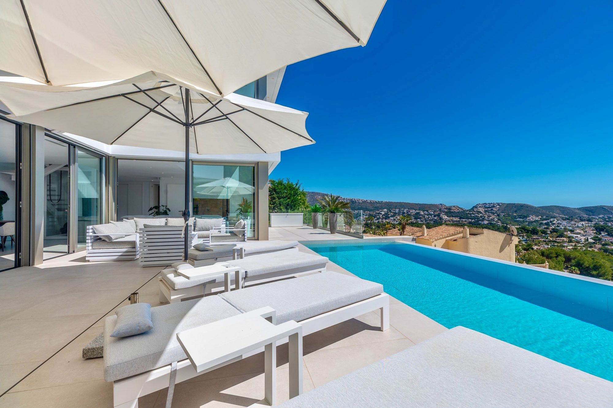 Poolterrasse mit Lounge und offener Glasfront zum Wohnbereich
